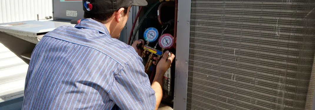 HVAC technician servicing a condenser unit in De Soto
