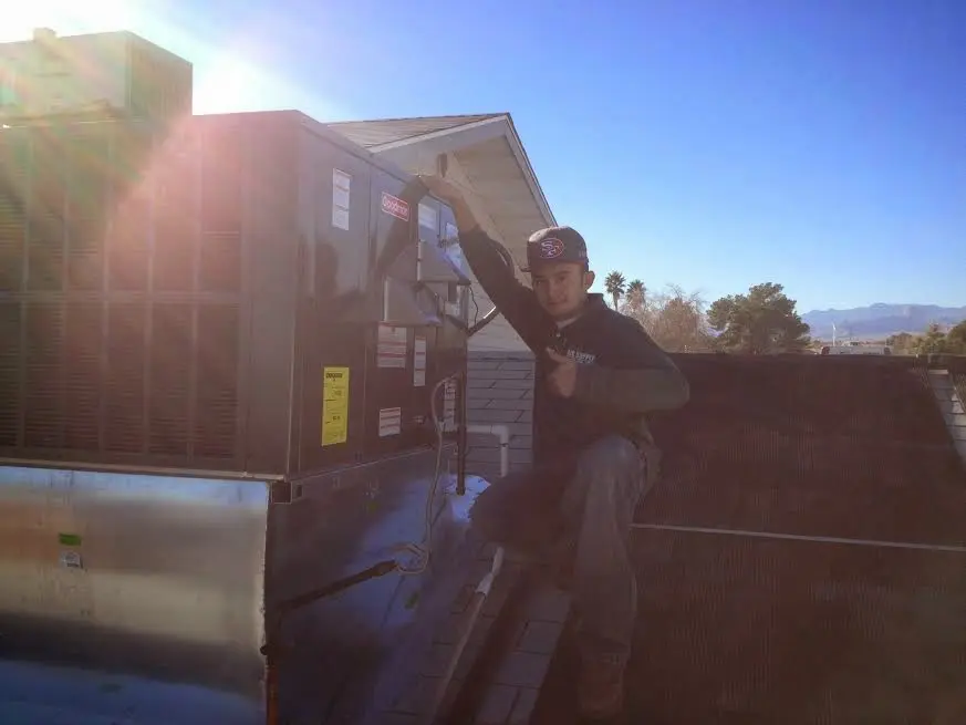 HVAC technician performing AC Tune-Up on a rooftop unit in De Soto